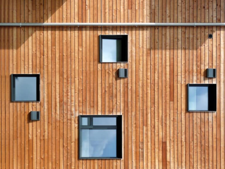 Bardage extérieur en bois naturel avec fenêtres carrées sur maison contemporaine