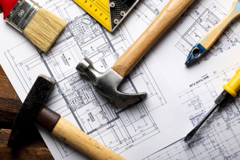 Plan de rénovation maison avec outils de chantier (marteau, pinceau) - Illustration avis TravauxMakers.fr